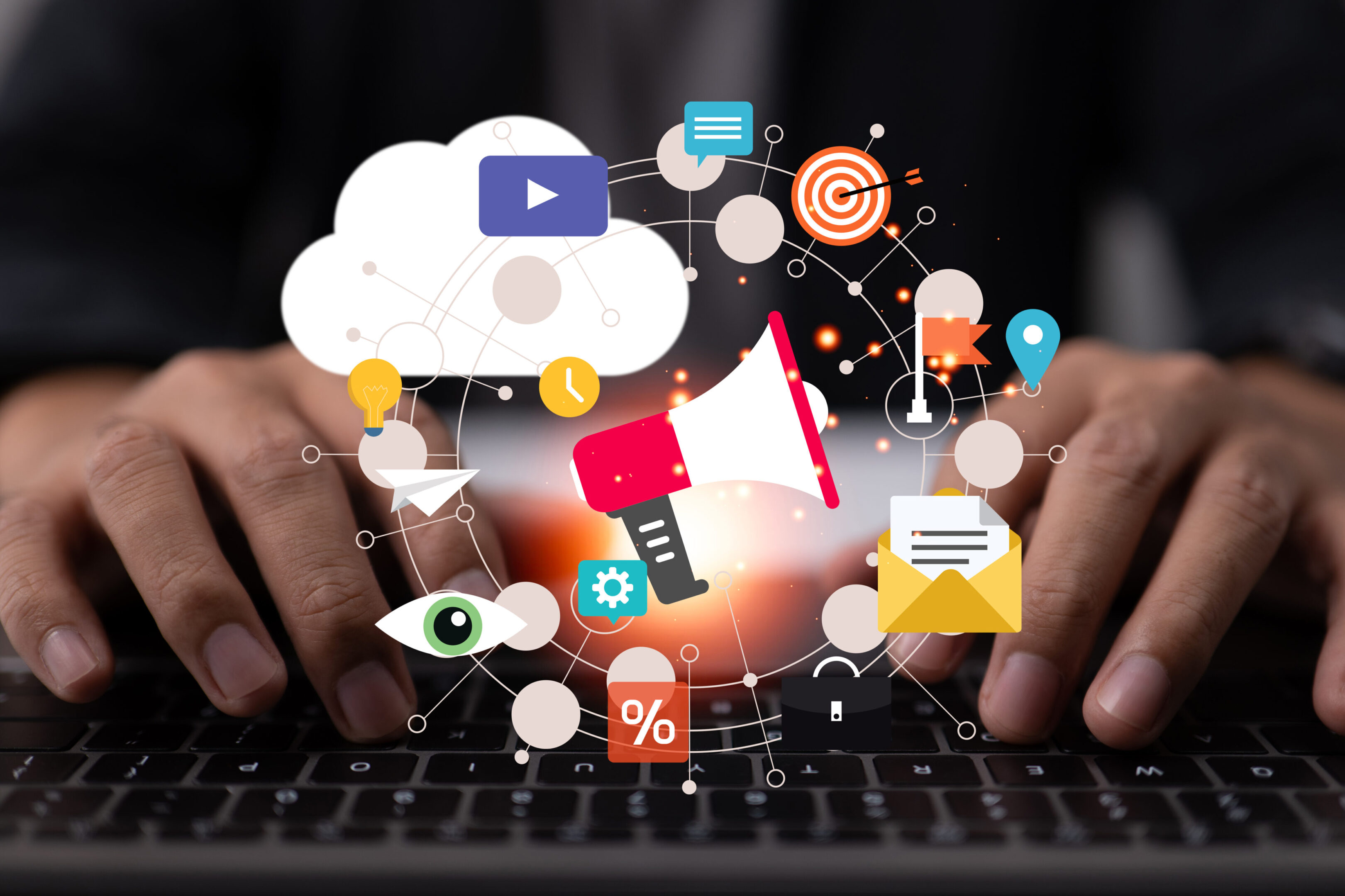 Digital marketing concept with social media icons and a megaphone over a laptop keyboard.